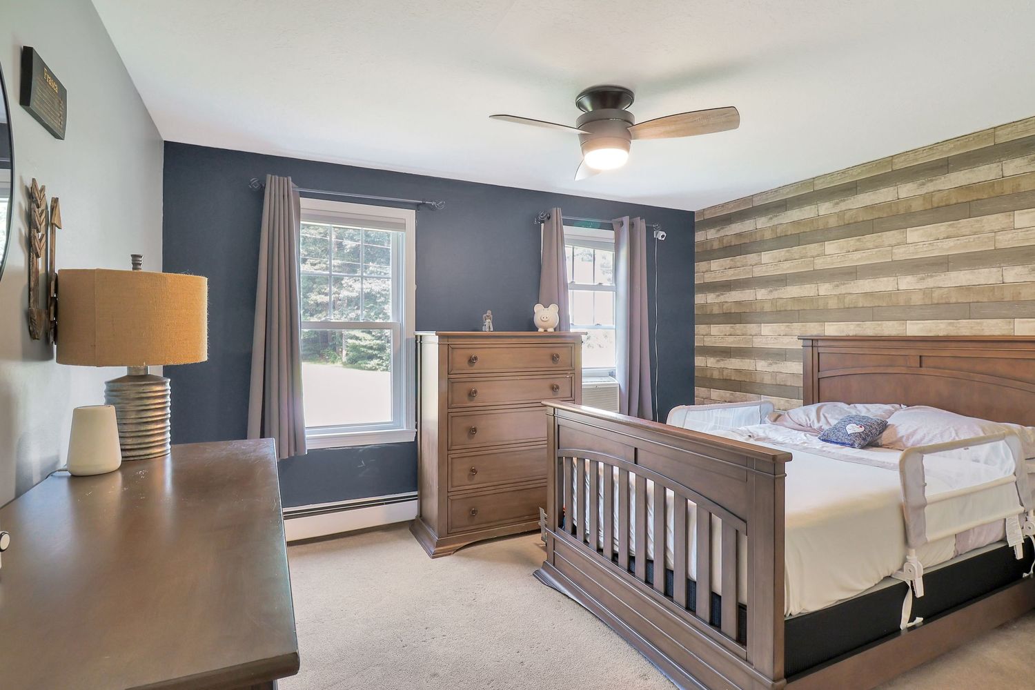Spacious bedroom with navy accent wall and wooden bed frame.