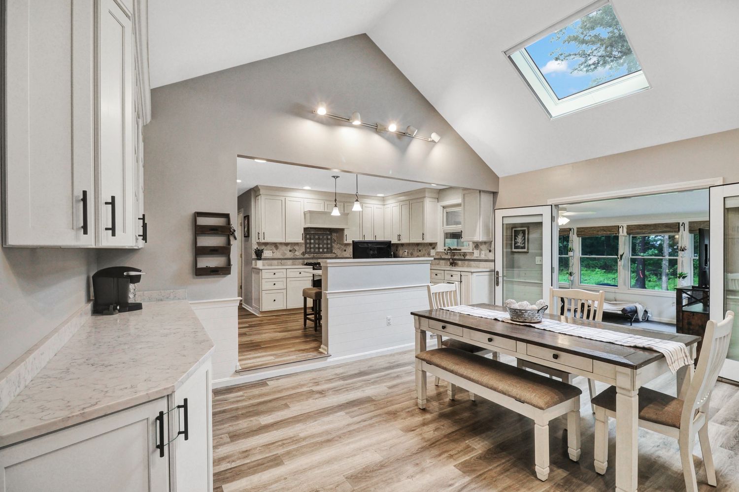 Open concept living space with white kitchen cabinets and hardwood flooring.