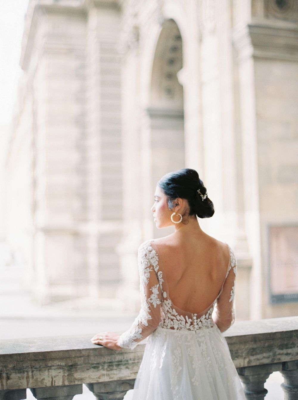 Bride in a beautiful wedding gown on a balcony at Louvre, Paris.