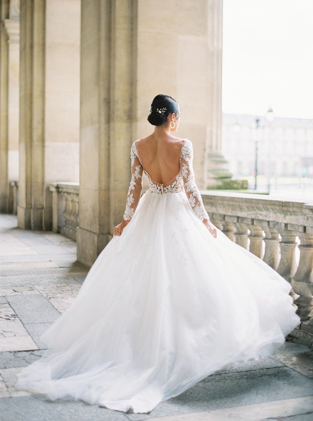 Elegant bride in wedding attire on a balcony at Louvre, Paris.