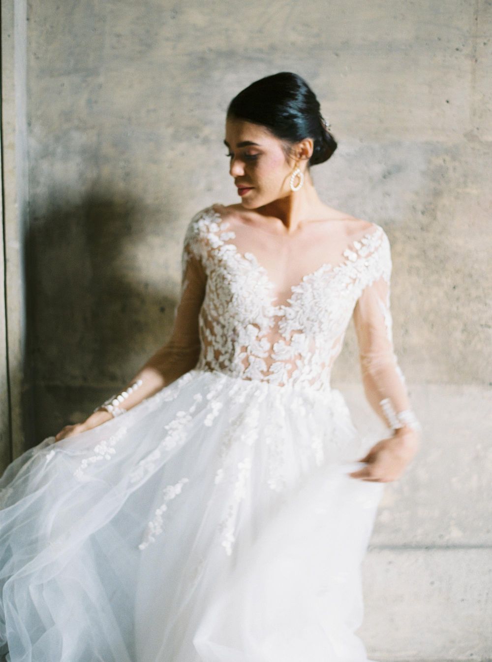 Bride in stunning gown standing near columns at Louvre, Paris.