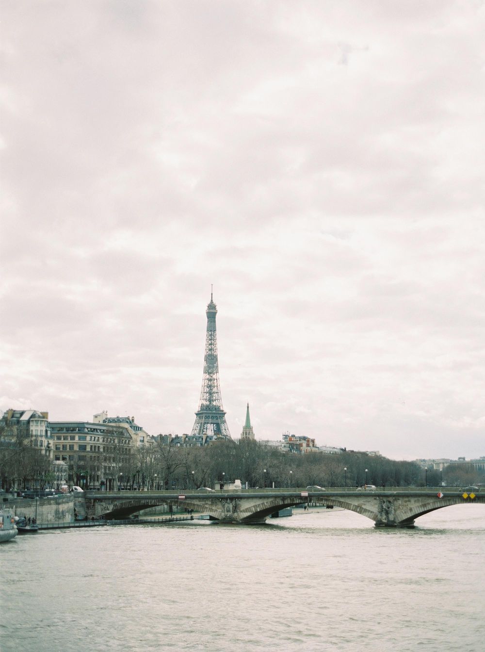 A river with a bridge and Eiffel Tower in the background in Paris.