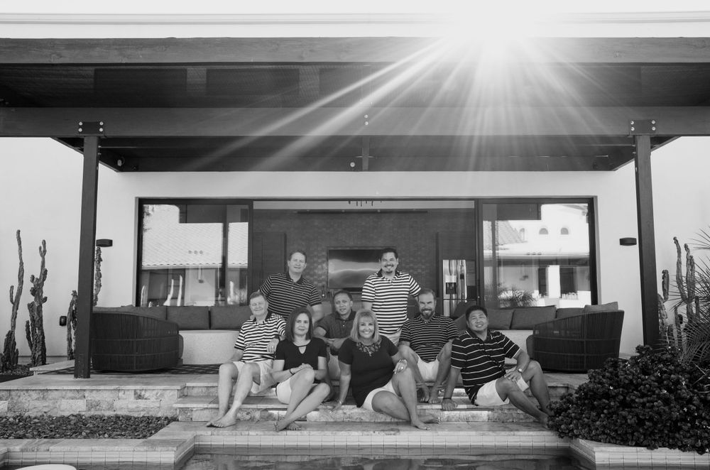Large family group poses together on patio poolside in black and white lifestyle portrait.