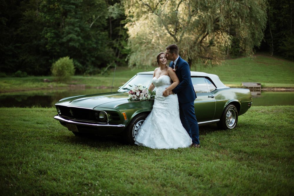 Romantic wedding photography session in a scenic outdoor setting with vintage cars.