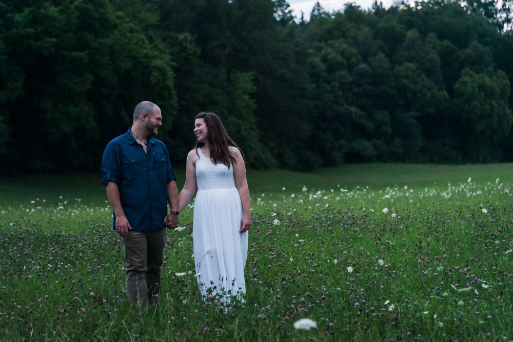 Couple walks through field while gazing at each other.