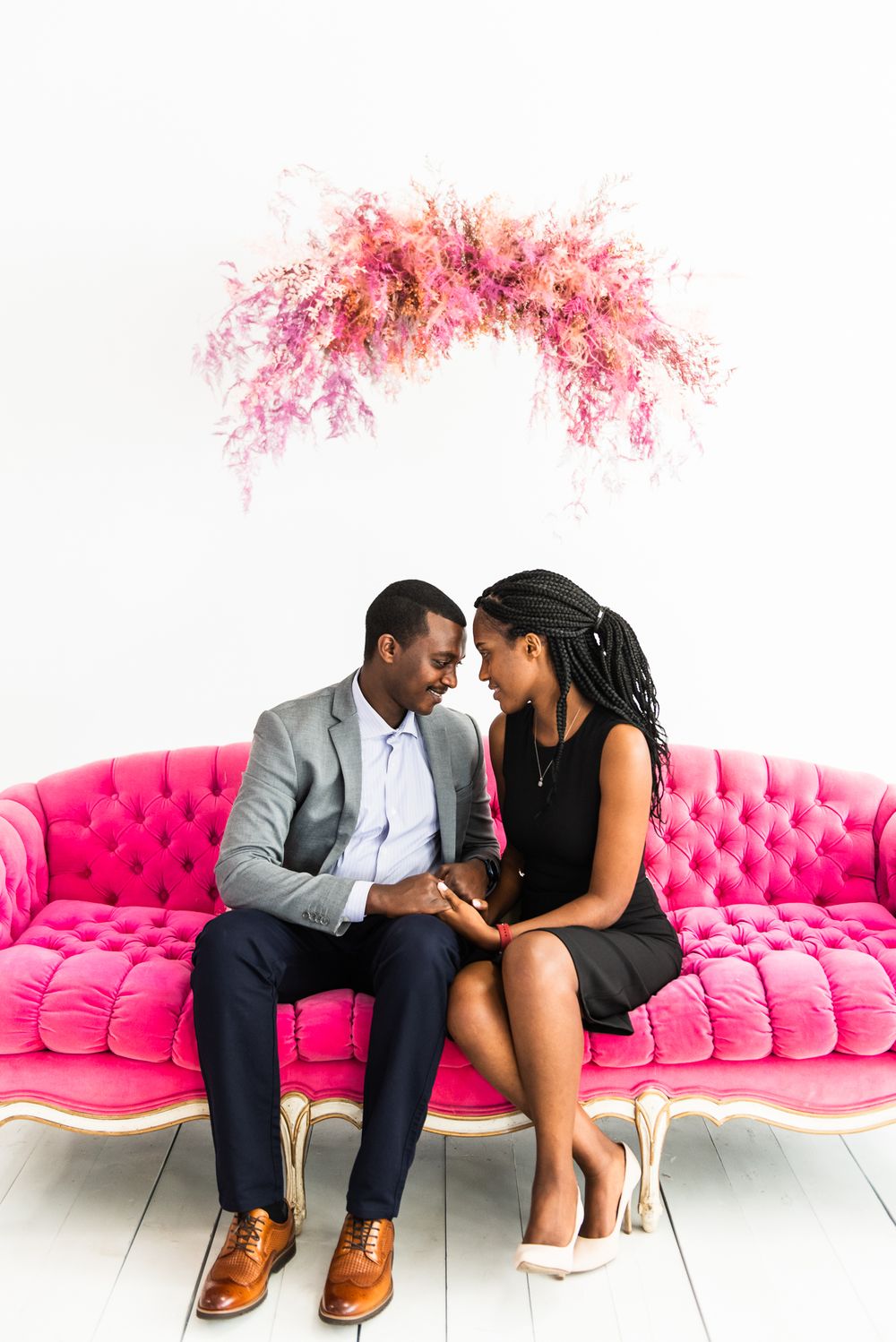 Couple touches foreheads on pink couch