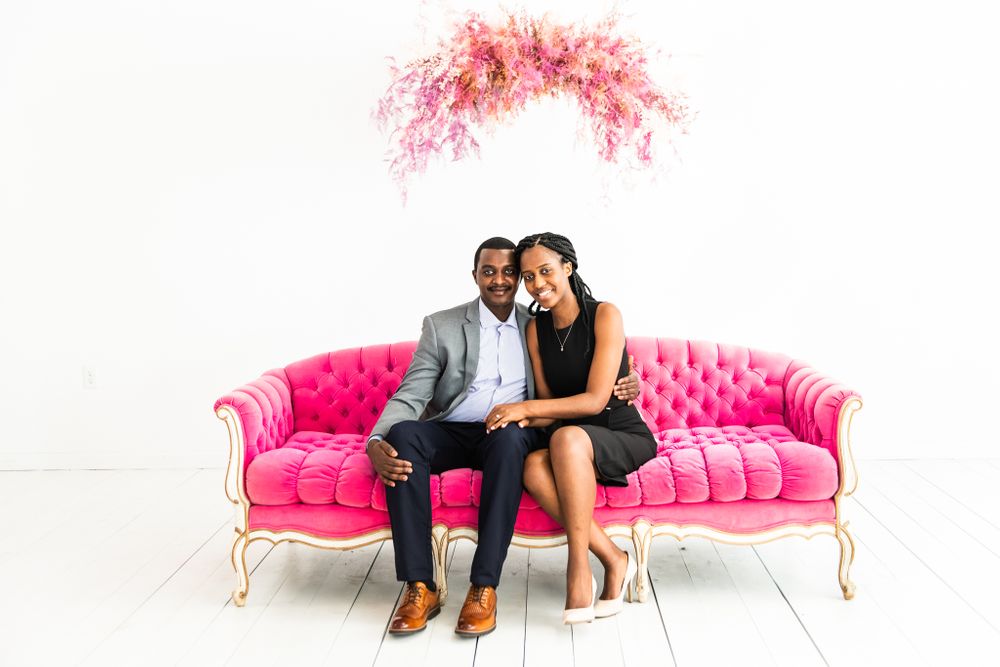 Couple sits and looks forward on pink couch