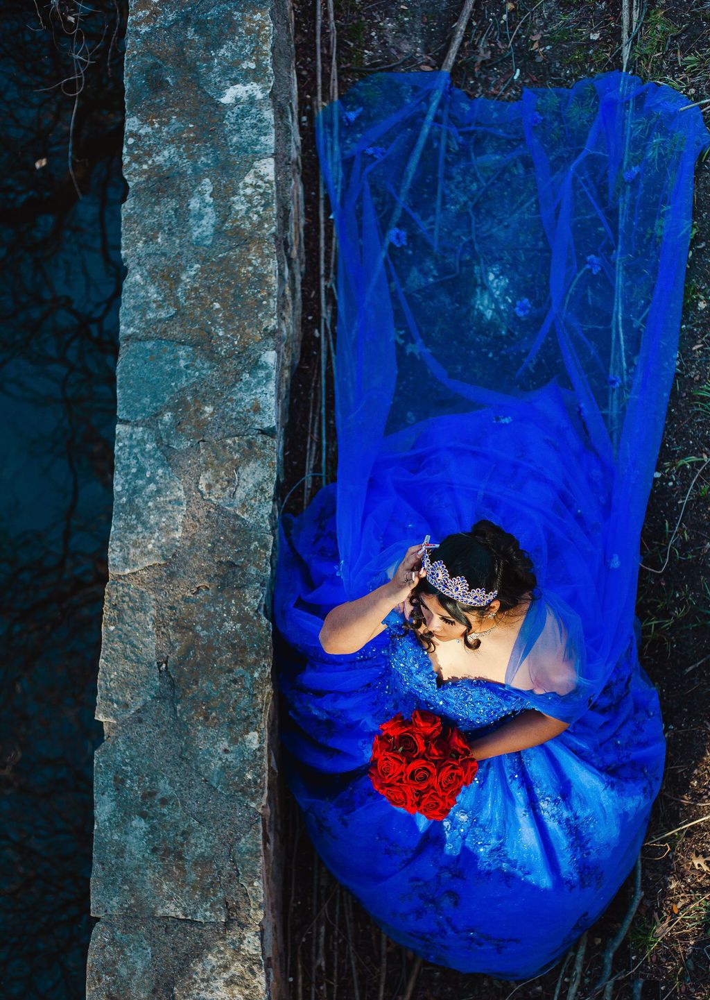 Una mujer con un vestido azul de quinceañera posa para el primer fotógrafo de xv años de dfw en Highland Park, Texas