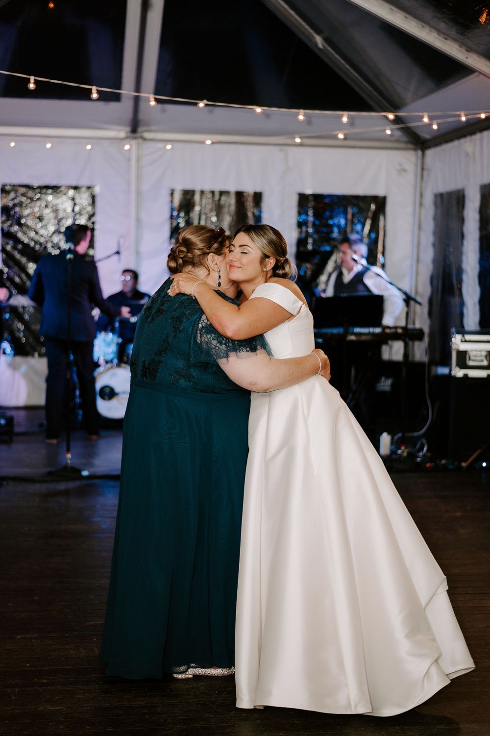 Couple sharing a romantic dance moment under twinkling lights at their wedding reception.