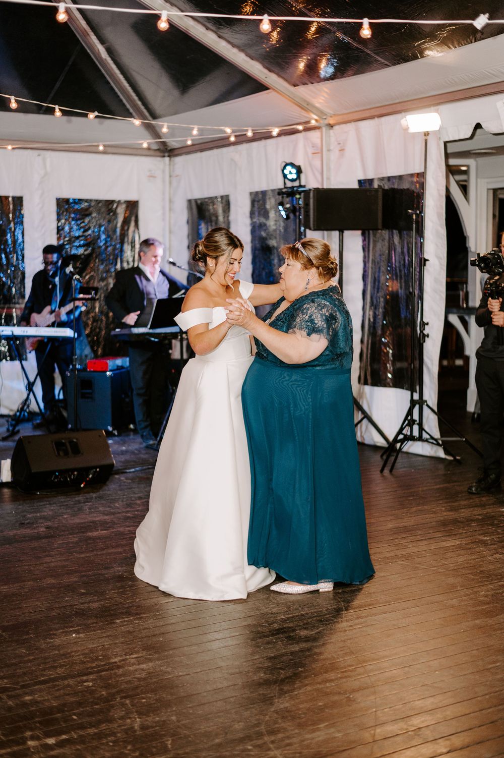 Wedding reception dance floor with string lights and wooden flooring.