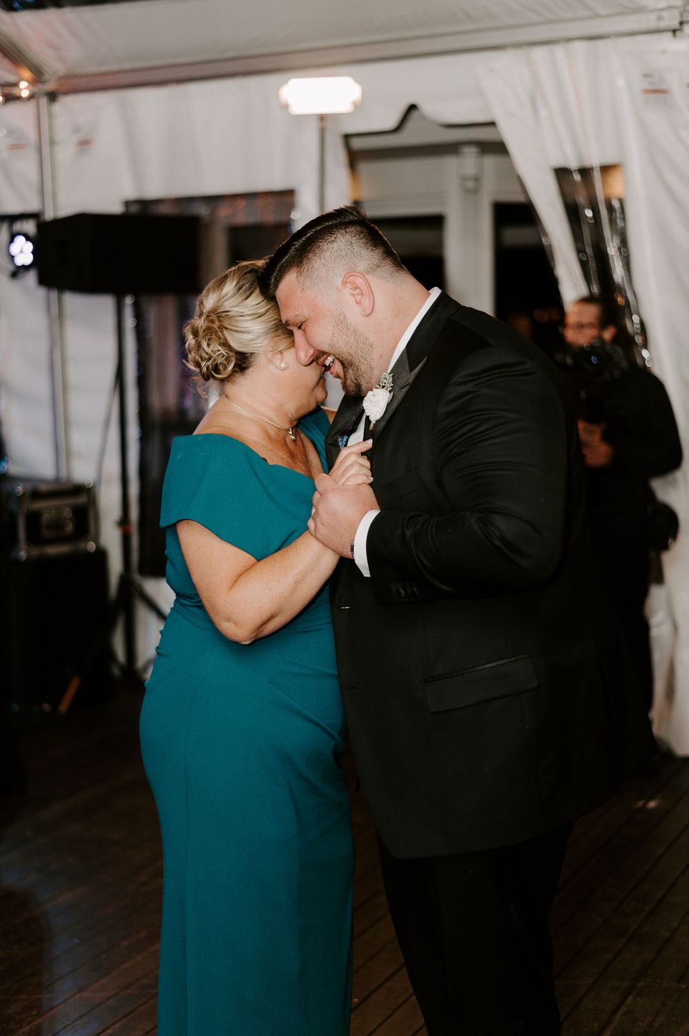 A couple shares a romantic dance moment in formal attire at an indoor venue.