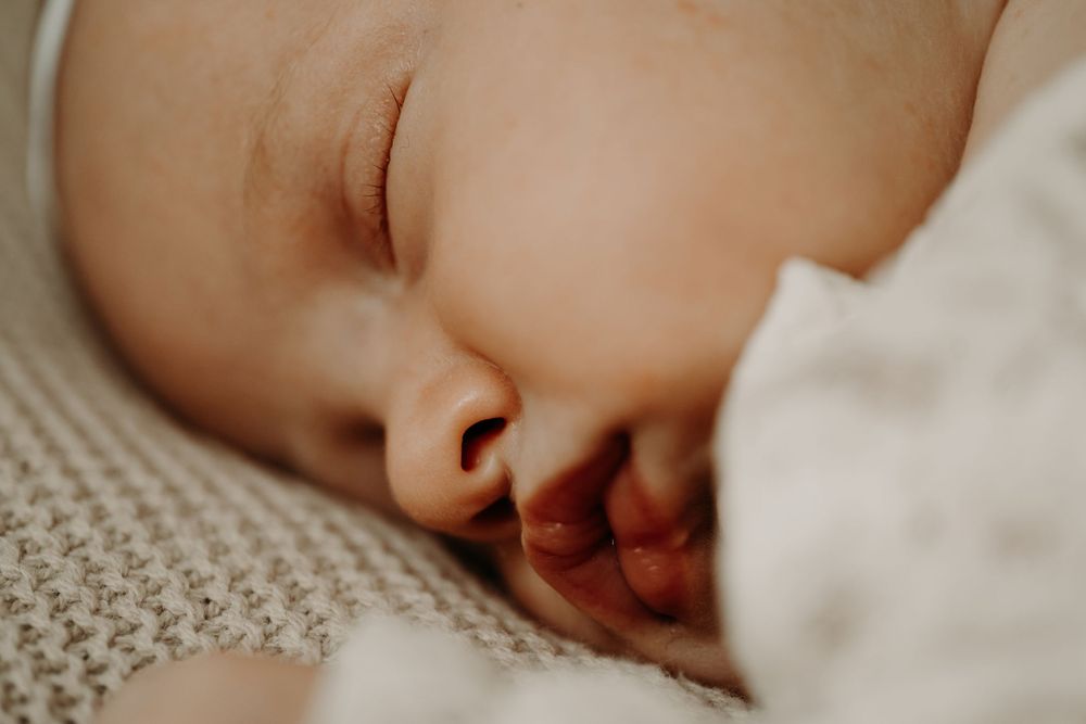 Close-up of peaceful sleeping baby's face against textured fabric.