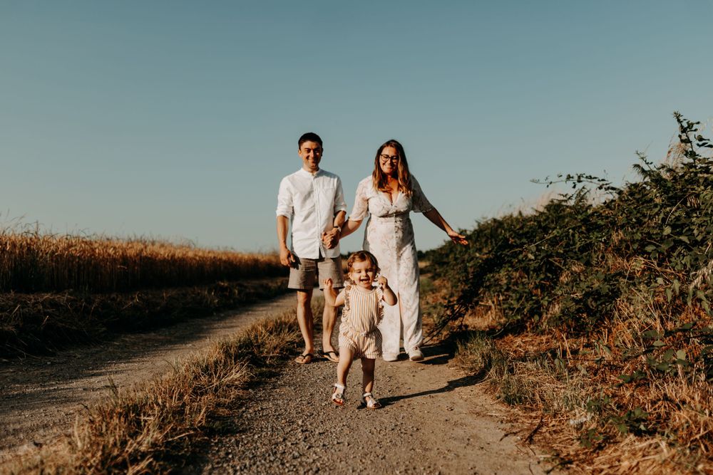 Family walking along a countryside path surrounded by tall grass.