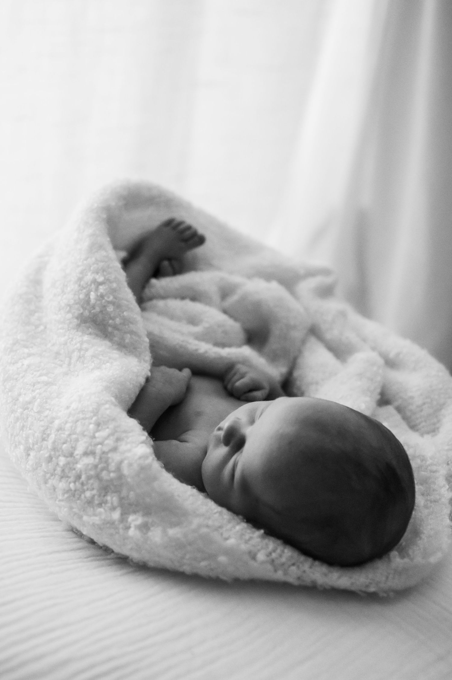 Simple black and white image of a newborn baby on a white beanbag