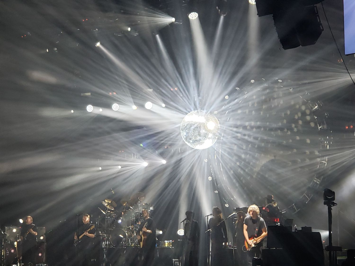 Concert stage with dramatic starburst lighting effect and silhouetted performers.