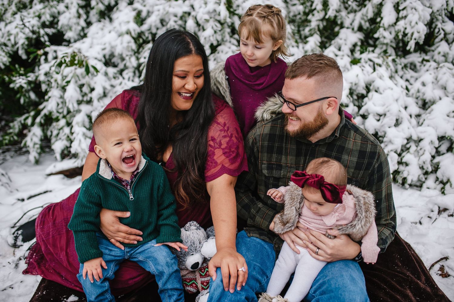 A family shares a joyful moment together seated in a snowy winter setting.