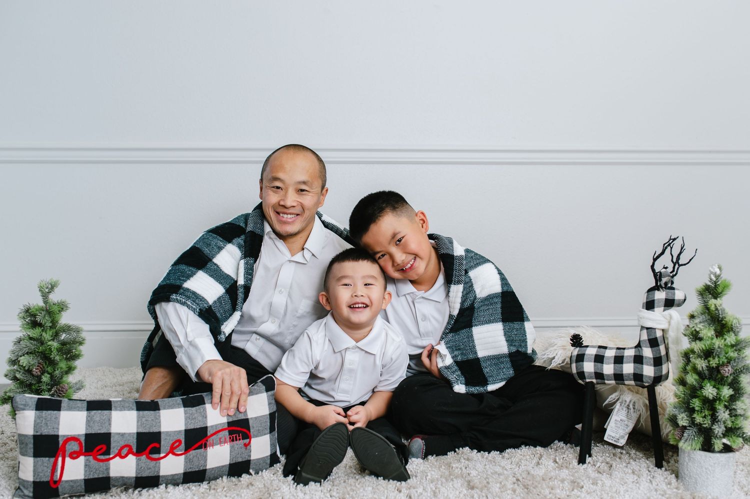 A cozy holiday portrait on white carpet with buffalo plaid decor and greenery.