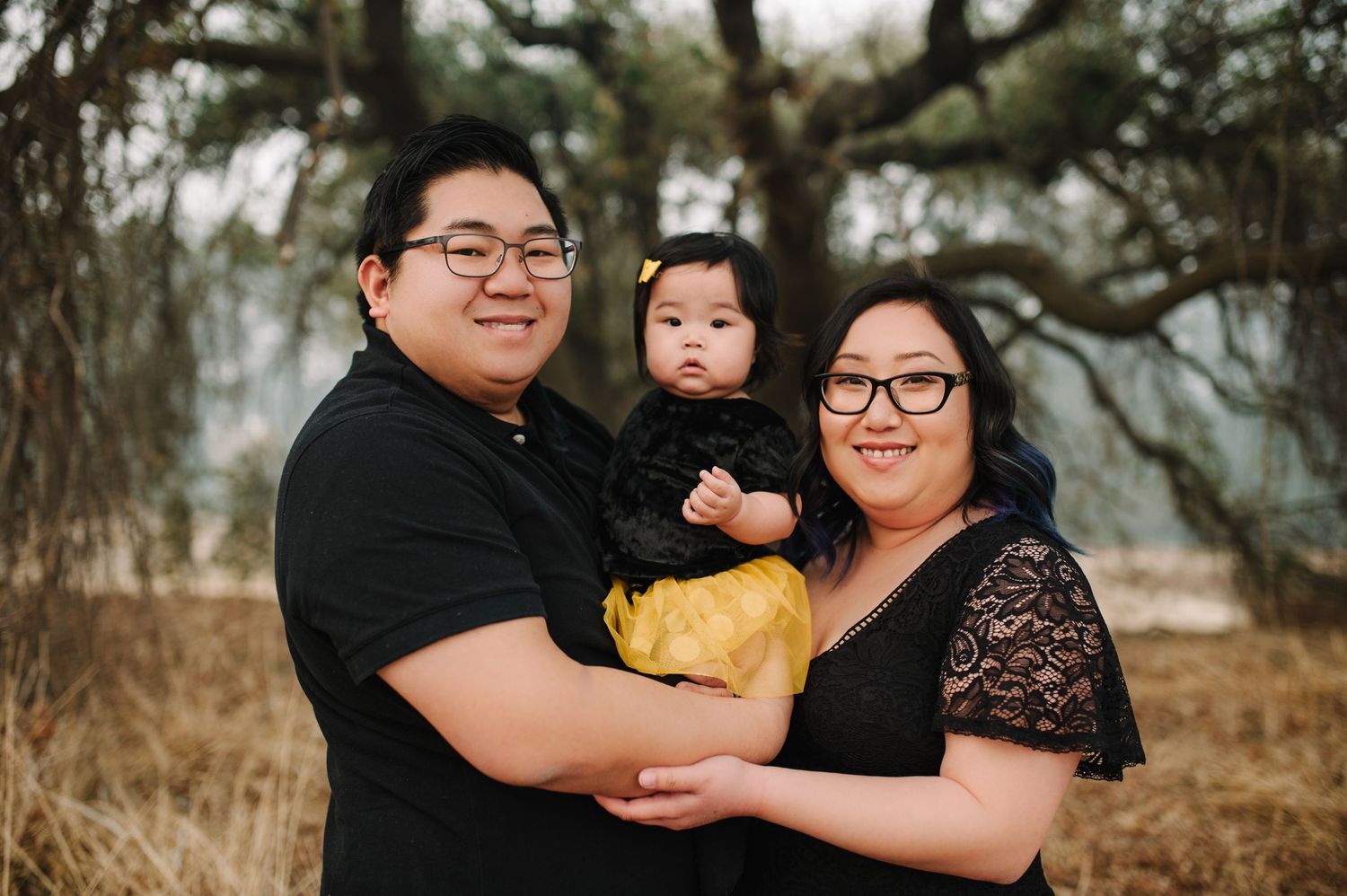 Family portrait captured against natural autumn backdrop with moody lighting.