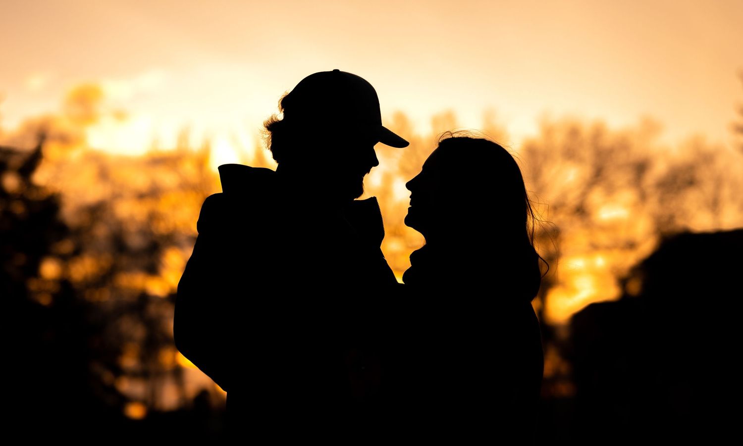 A romantic silhouette of a couple against a golden sunset backdrop.