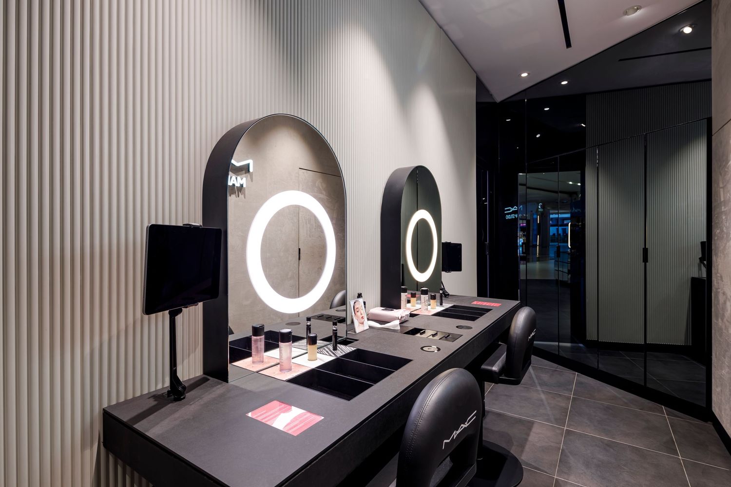 Modern makeup vanity station with circular LED mirrors and black countertop.