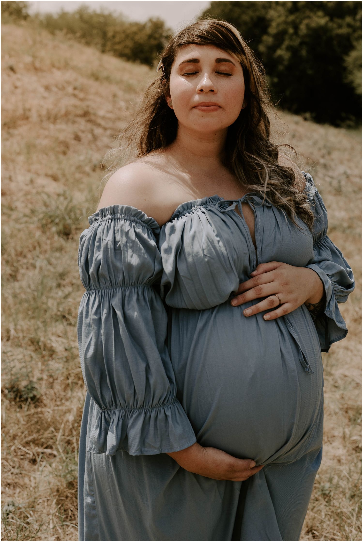 Intimate maternity portrait with soft lighting and blue off-shoulder dress.