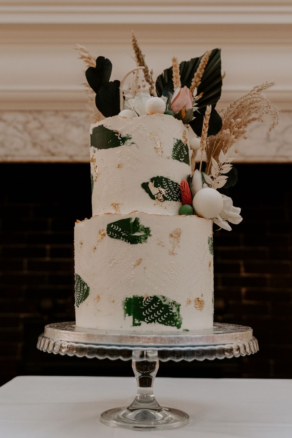 a wedding cake. 3 tiers. White icing and green leave pattern.