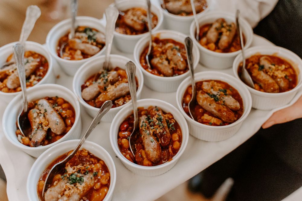Wedding canapes. Small pots of food - sausage and beans.