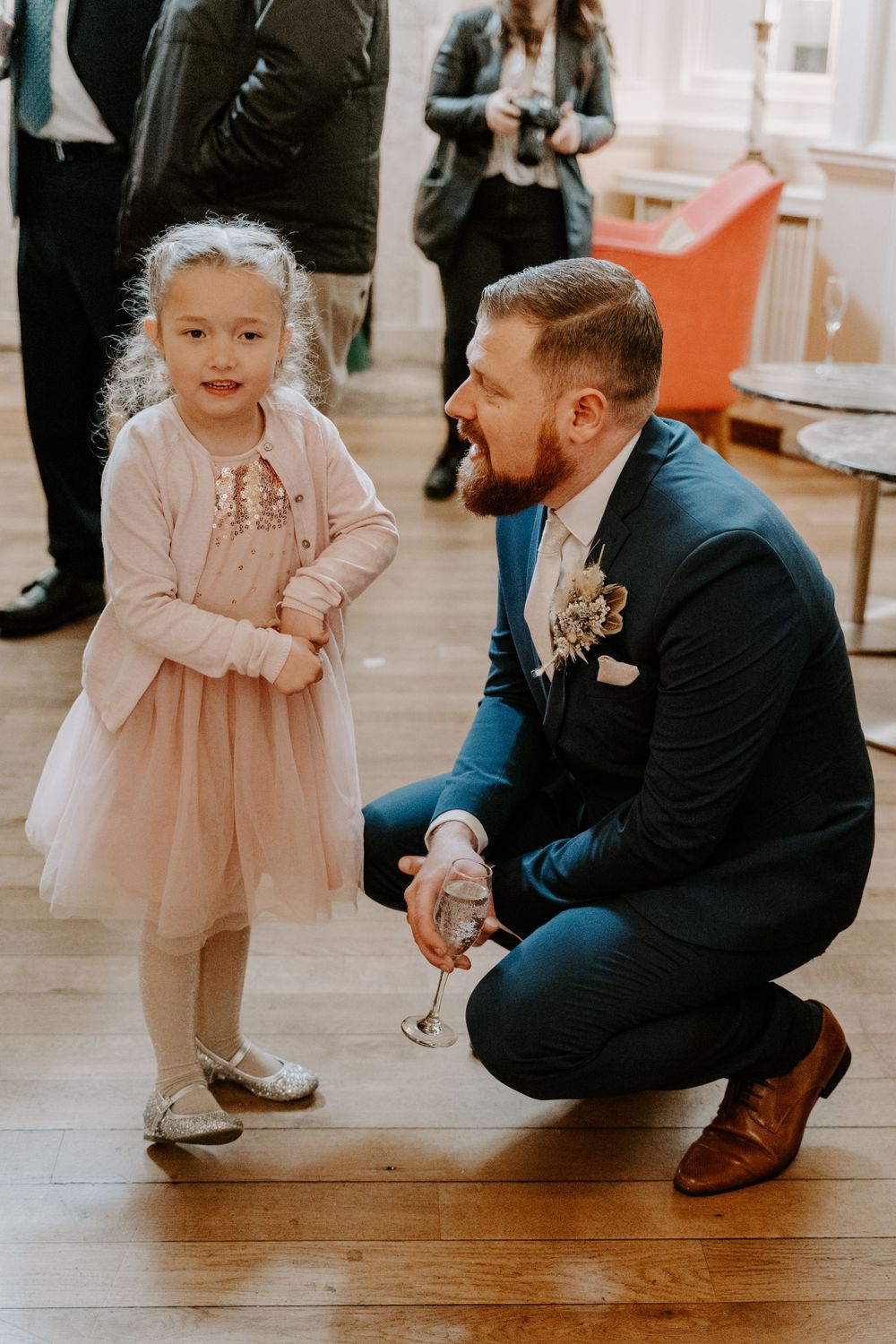 a Groom knelt down, talking to his niece at his wedding.