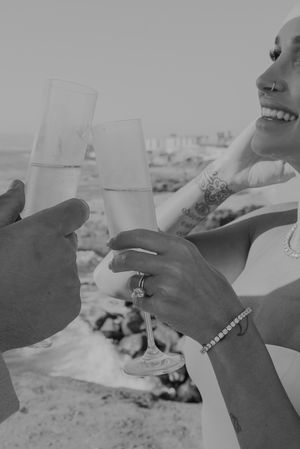 Champagne glasses clinking together in celebratory toast with ocean view.