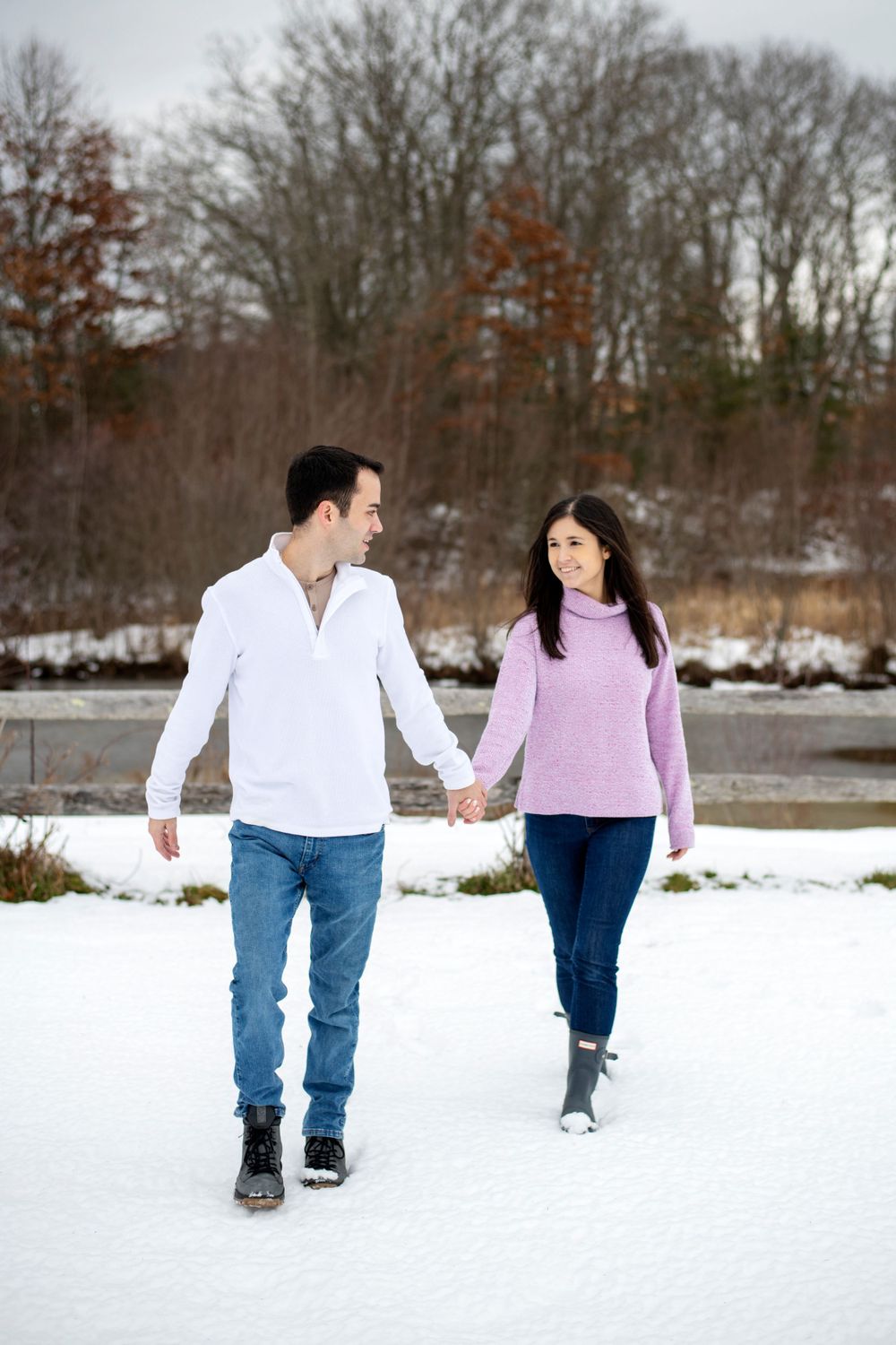 Engaged couple walking hand in hand through the snow during a winter Massachusetts engagement session