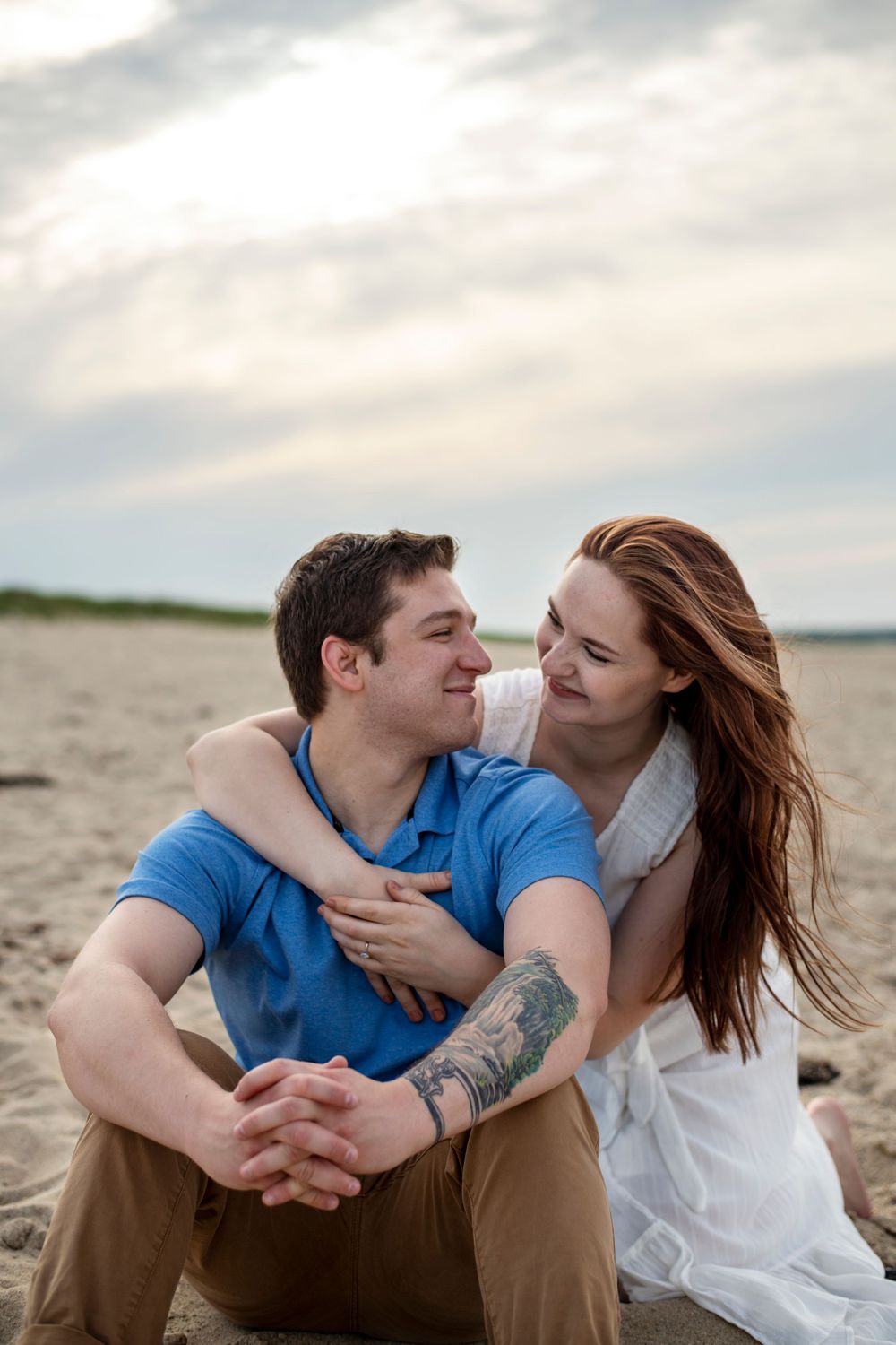 Engaged couple cuddling together on the beach during a relaxed New England engagement session
