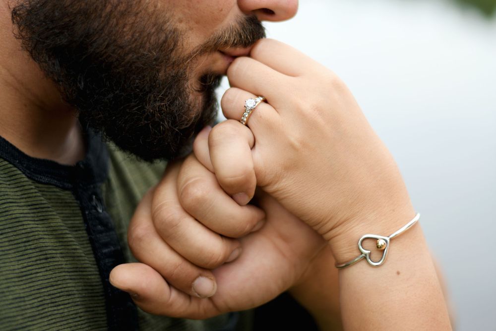 Close-up of a man kissing his fiancée's hand, highlighting her diamond engagement ring