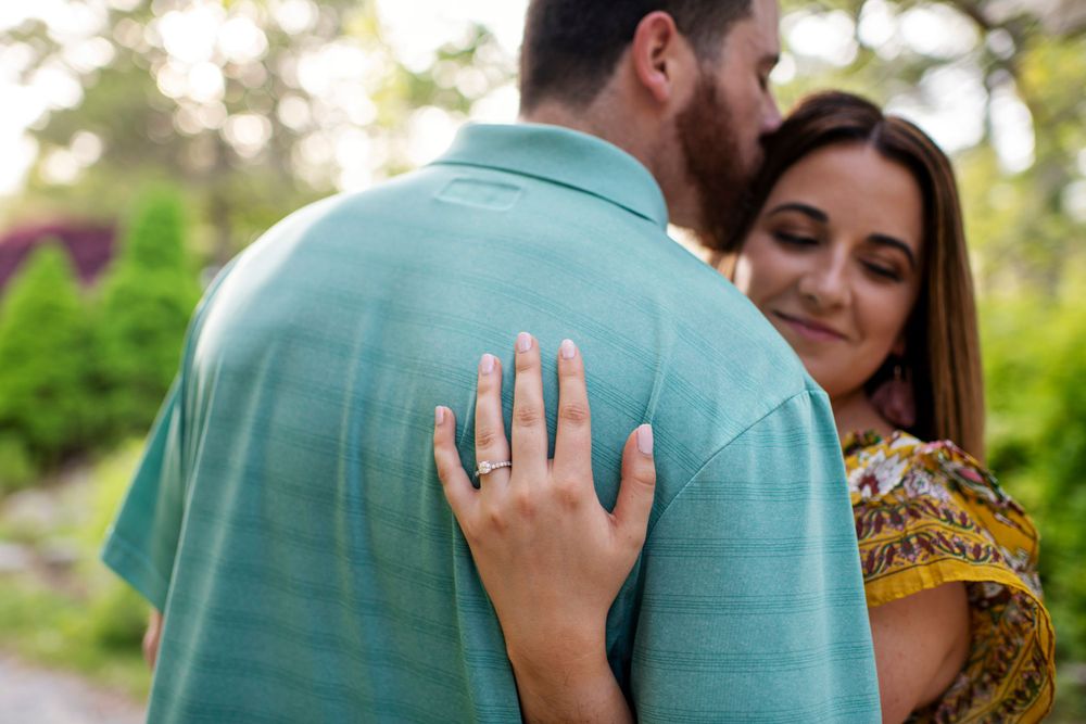 Close-up engagement portrait highlighting a woman's diamond engagement ring as she embraces her fiancé at Borderland State Park