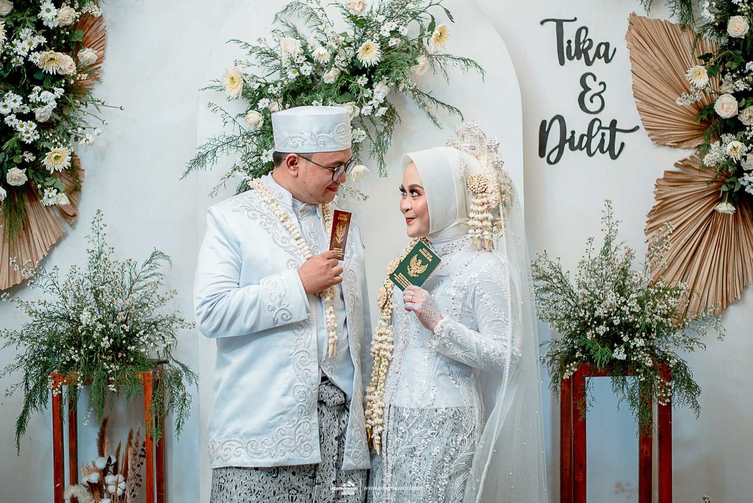 Couple in matching white outfits speaking into microphones during wedding ceremony.