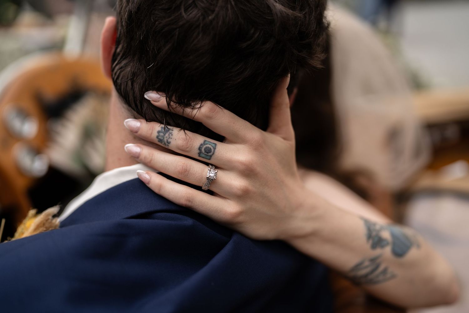 Close up of wedding rings and tattoos as couple embraces during romantic moment.