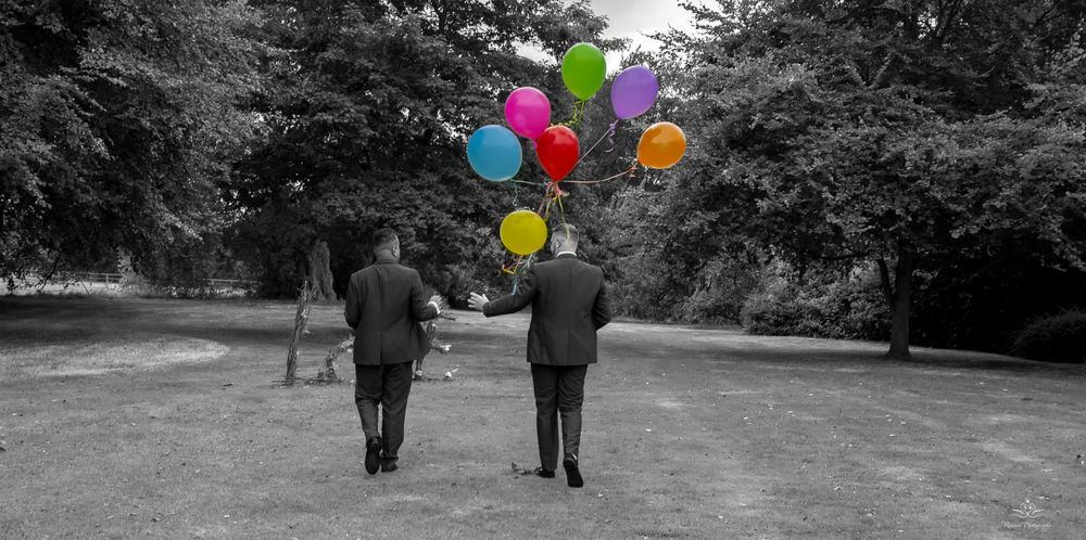 Selective color photo showing colorful balloons against a black and white wedding scene.