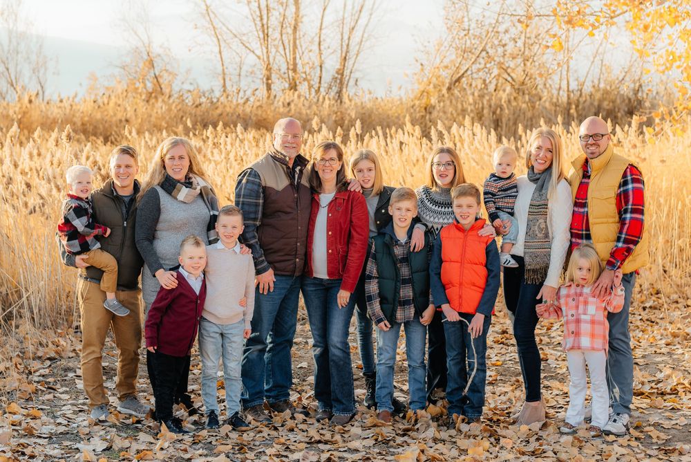Extended family group portrait standing among golden grasses and fallen leaves in autumn. Megan Snell Photo Utah Weddings