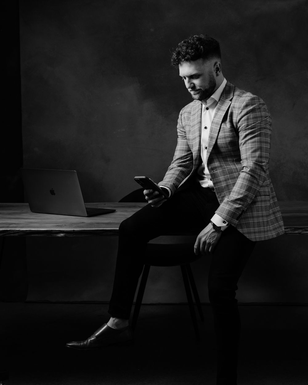 Dramatic black and white photos of person in checkered suit sitting thoughtfully.