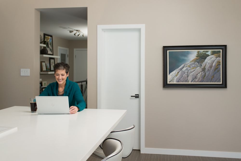 Modern white office space with person working at laptop and framed artwork on wall.