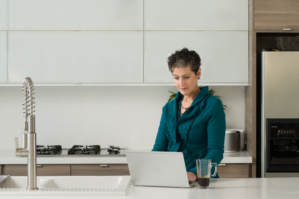 Modern white kitchen interior with person seated at counter.
