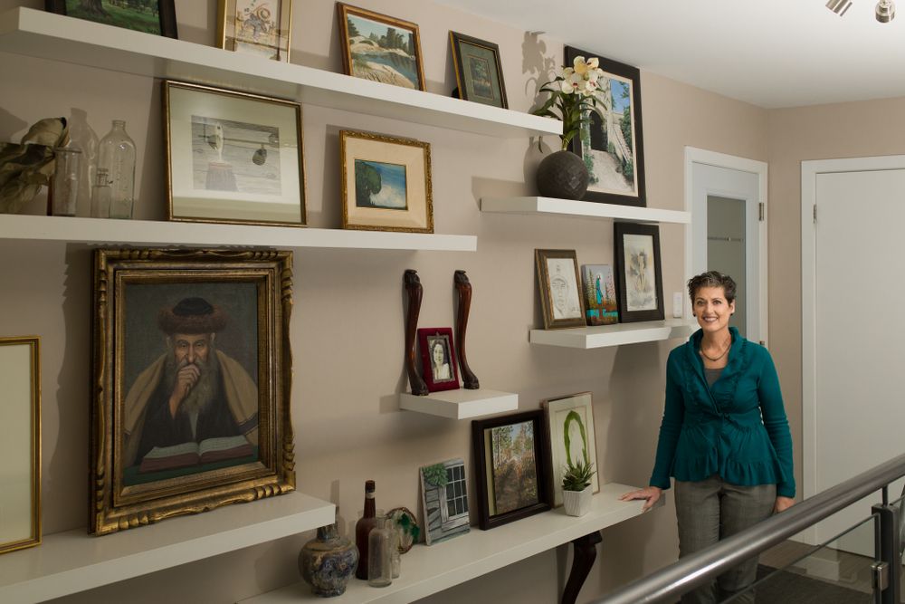 Wall display with framed artwork and photographs in home setting.
