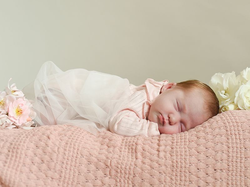 New born baby sleeps on pink blankets surrounded by garden roses, photography by Abigail's Studio in Buckinghamshire