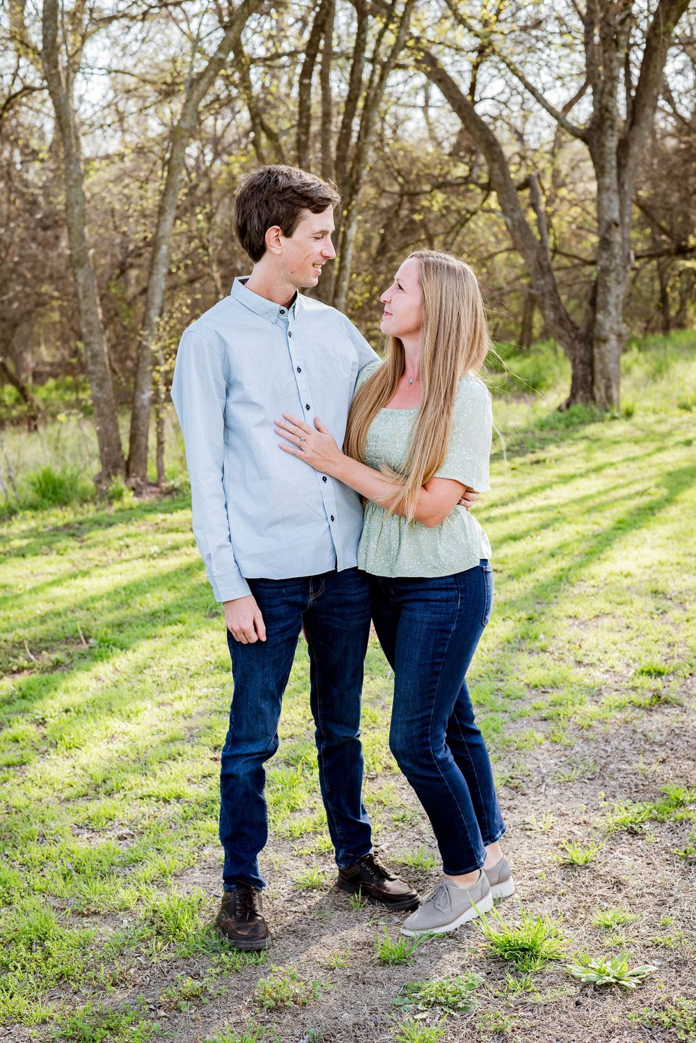 A young couple shares an intimate moment on a sunlit nature trail.