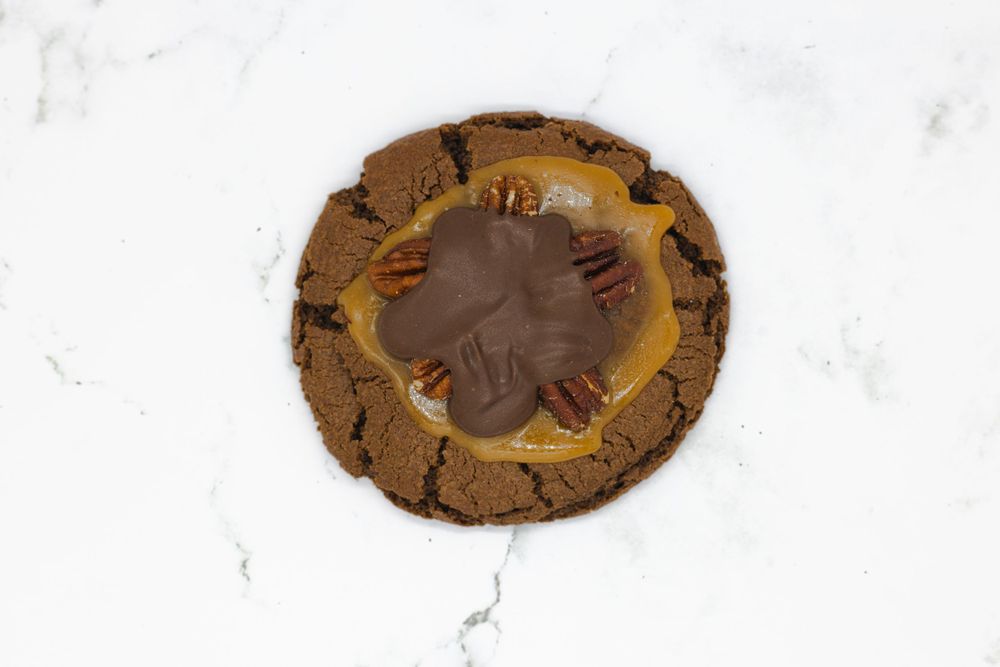 A round chocolate cookie with decorative patterns on a white marble surface.