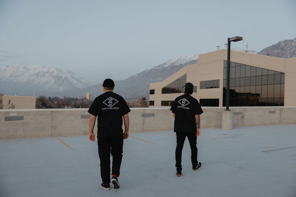 Two people walking on a rooftop with mountains visible in the distance.