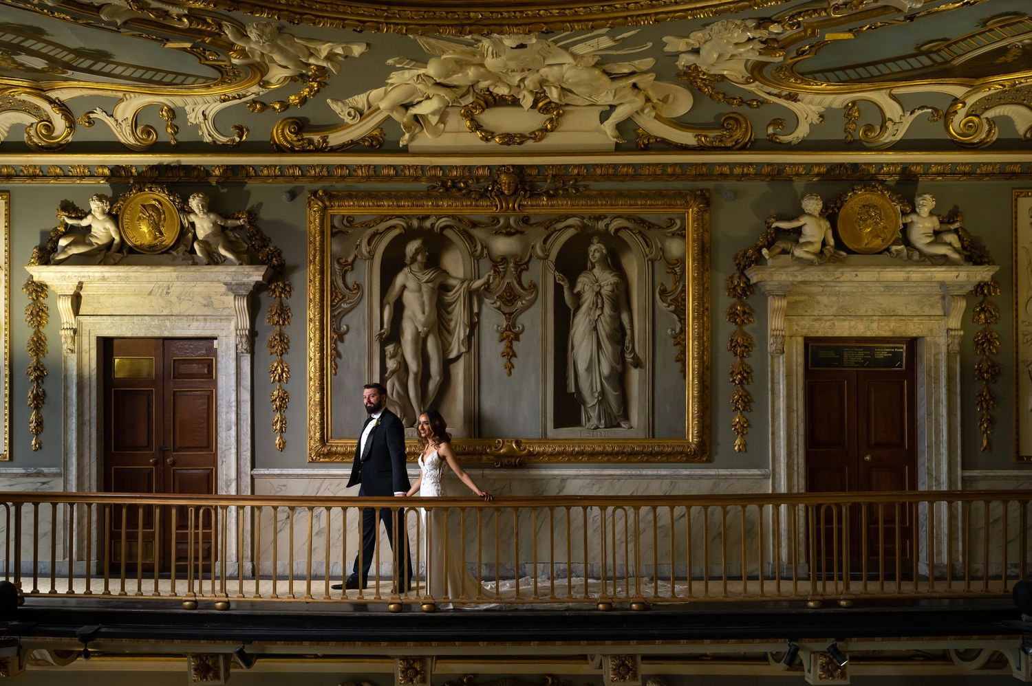 Detailed view of ornate classical architectural moldings and gold leaf decorations in a historic room.