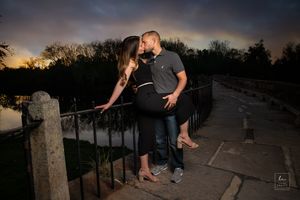 Romantic couple silhouetted against sunset sky on stone balcony.