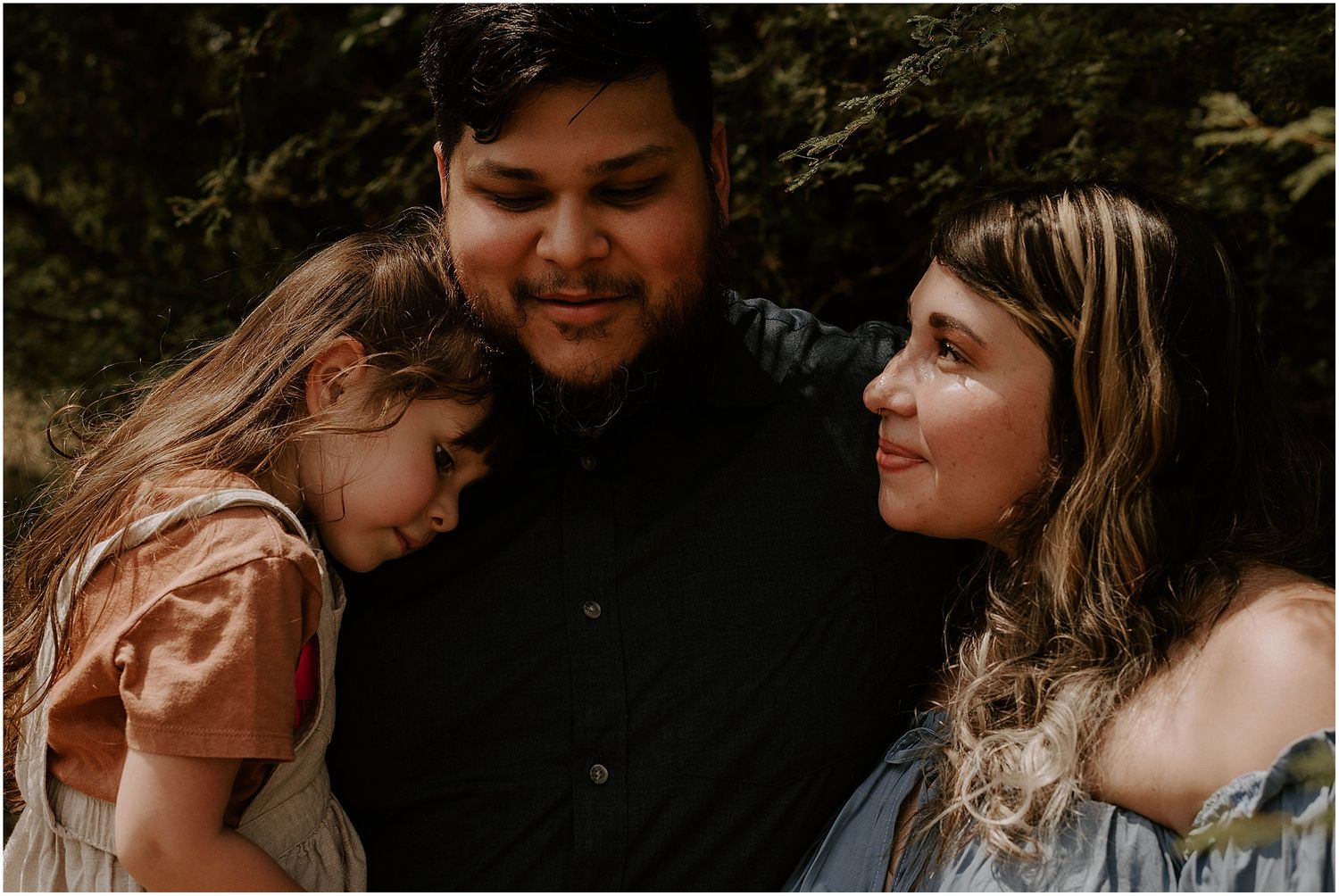 Candid moment captured of family members sharing tender embrace in natural setting.