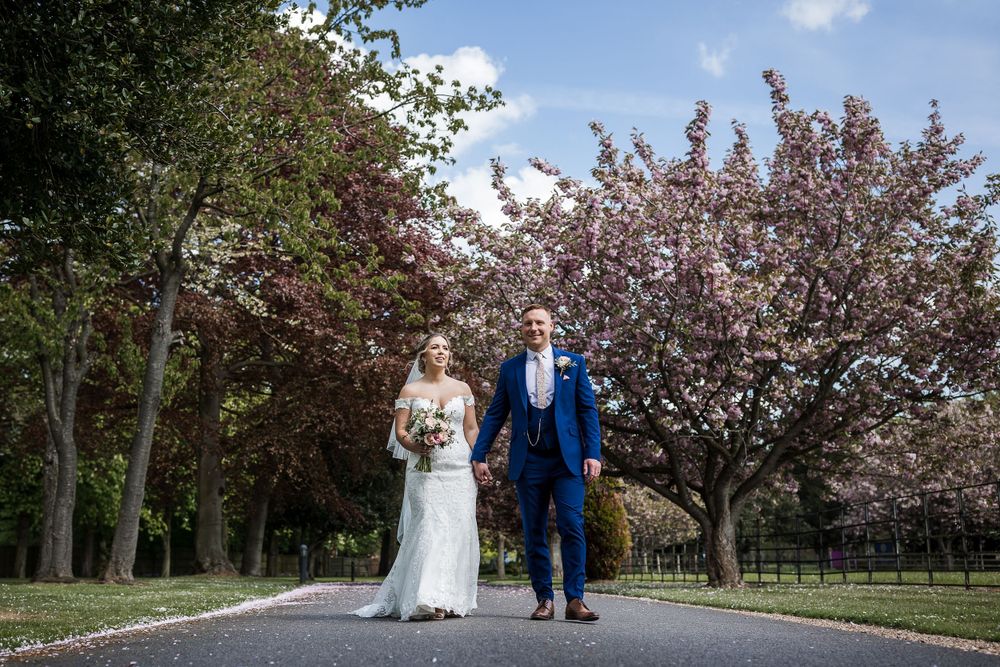 Bride and Groom walking past the cherry blossom trees at Kelham House