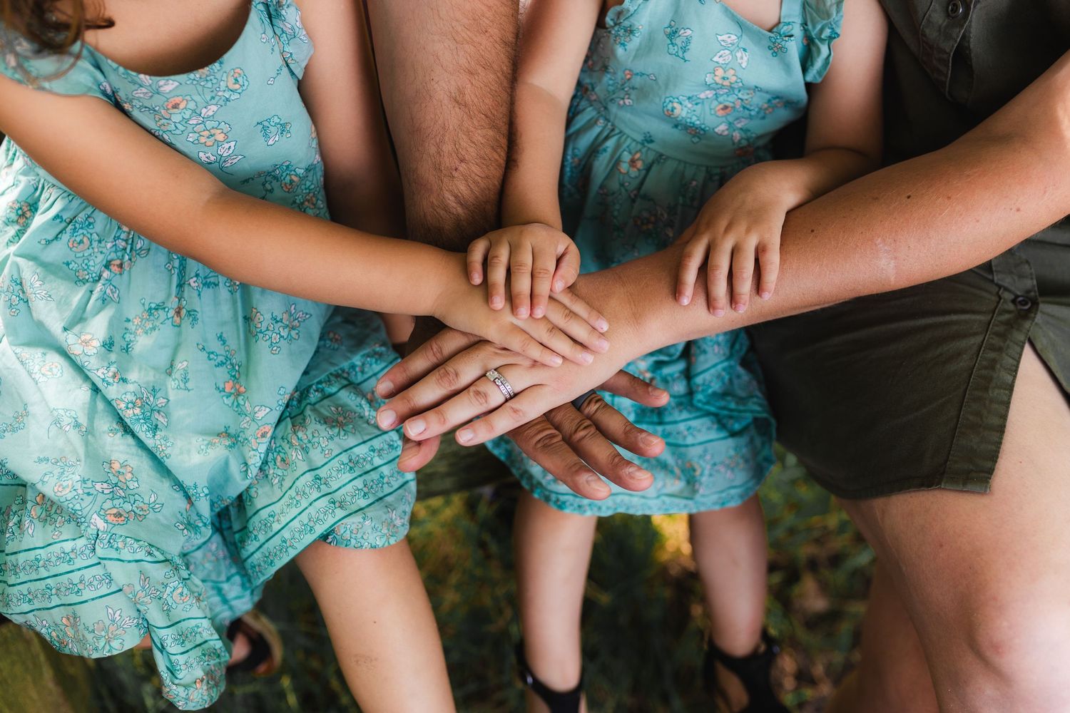 Close-up of a family of four's hands stacked on top of one another.
